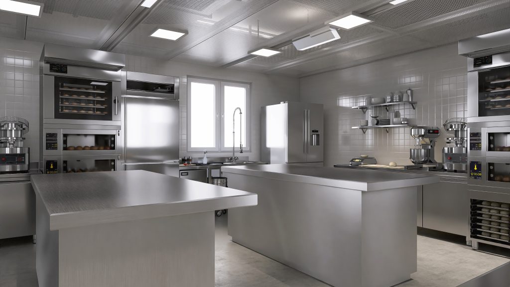 A clean commercial kitchen with stainless steel prep tables, cooking equipment, and organized workstations.