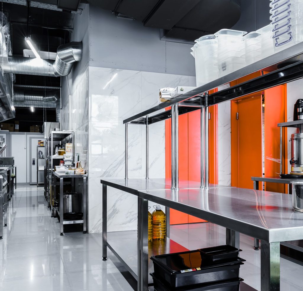 A commercial kitchen featuring a grease trap system and stainless steel equipment for restaurant operations.
